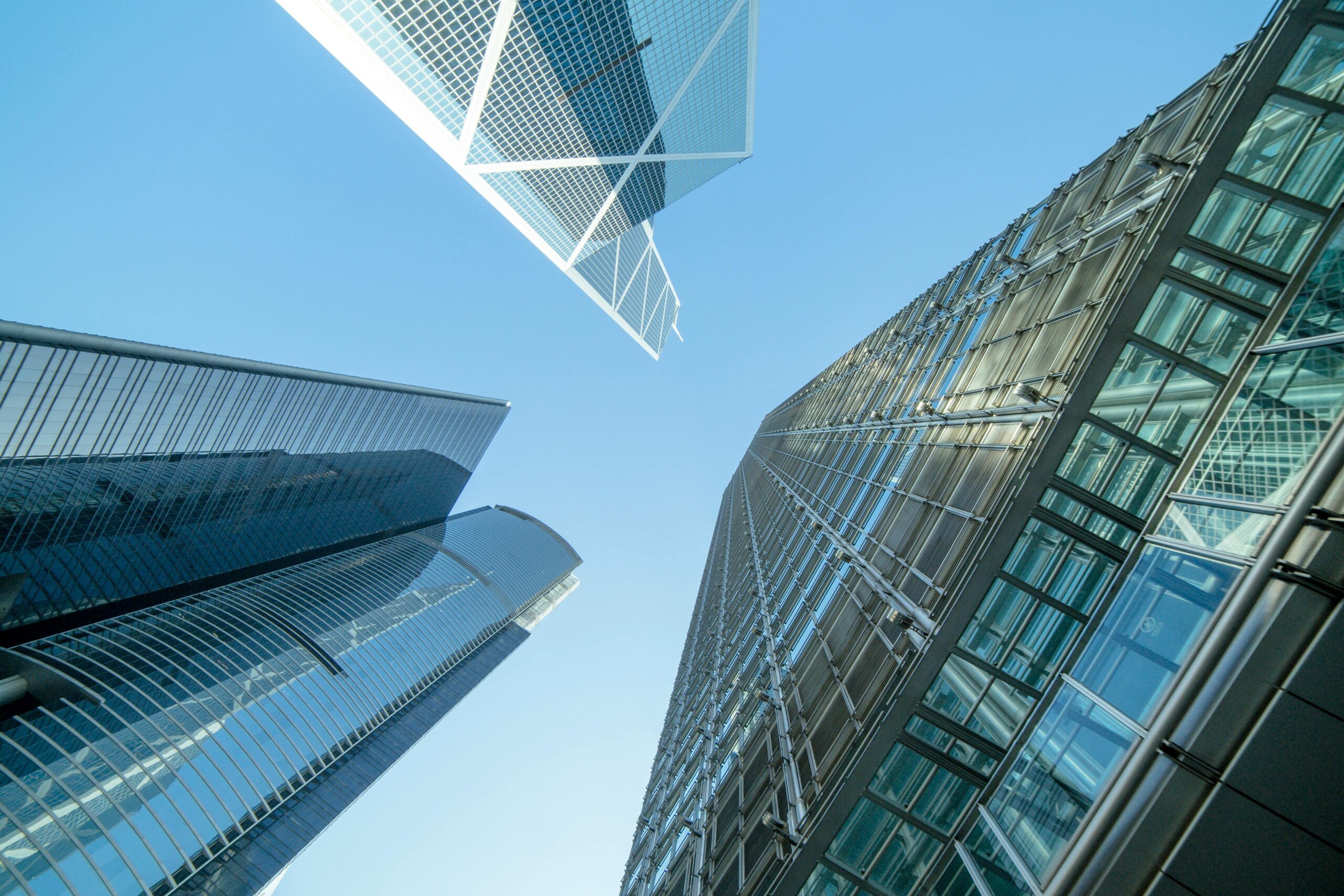 Upward view of modern glass skyscrapers against a clear blue sky.